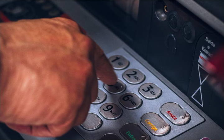 Mão digitando a senha em um caixa eletrônico